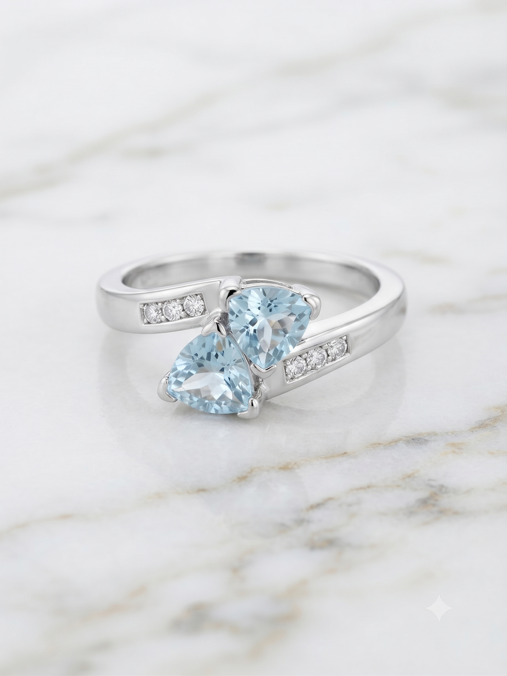10K white gold dual blue topaz bypass ring with diamond accents on marble surface